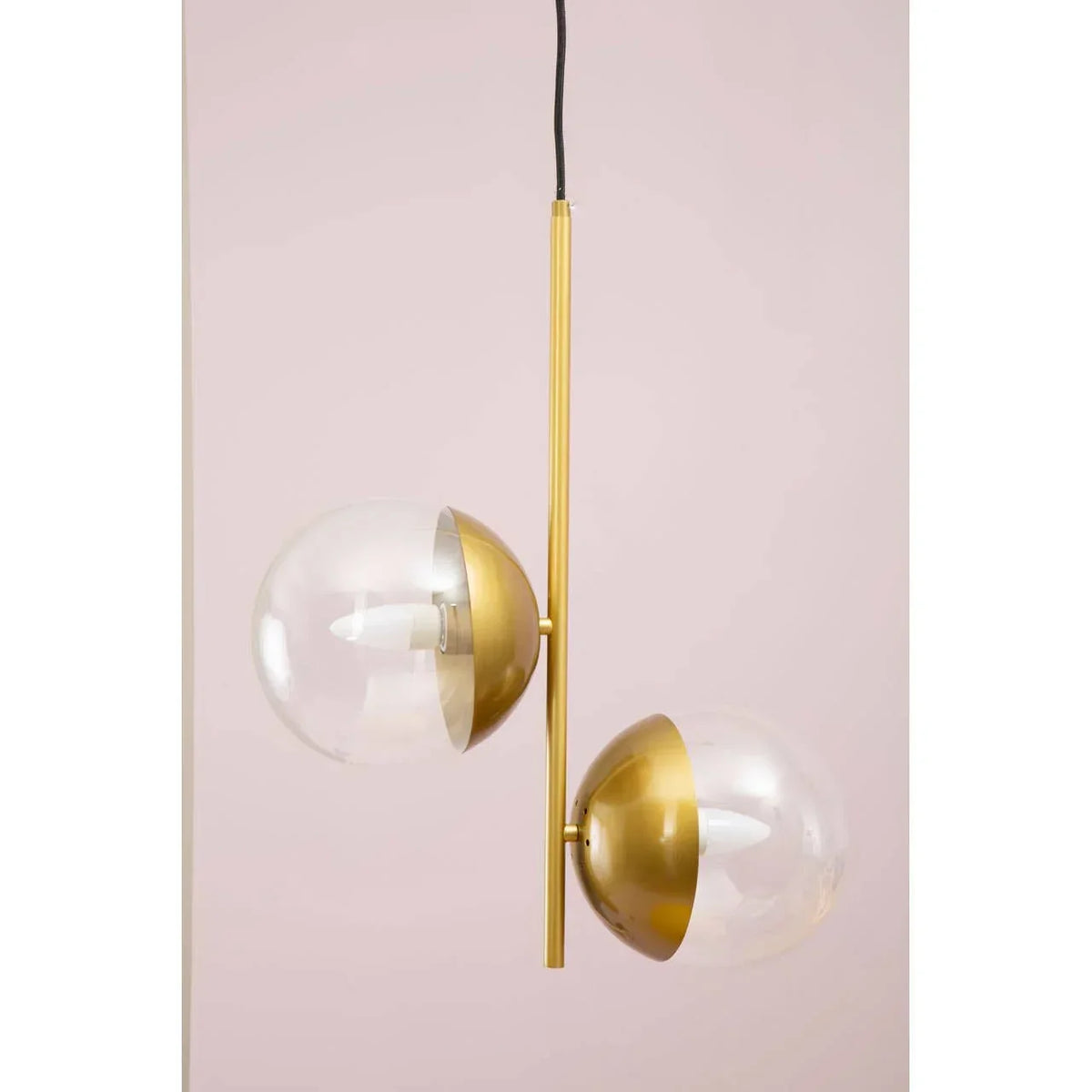 Modern pendant light with gold metal rod and two glass globe shades on pink background