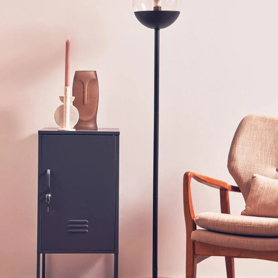 Modern black metal storage cabinet beside globe floor lamp and wooden accent chair