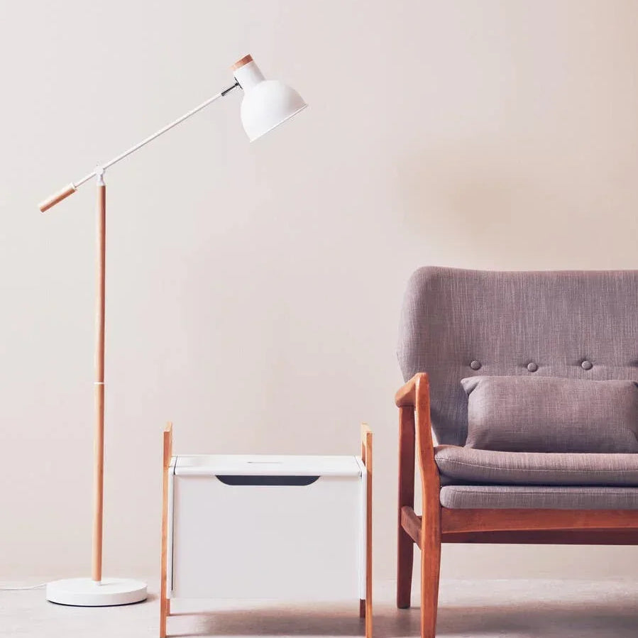 Modern grey fabric armchair with wooden frame, white side table, and floor lamp