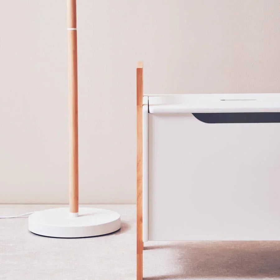 Modern white floor lamp beside minimalist wooden bed frame on light carpet