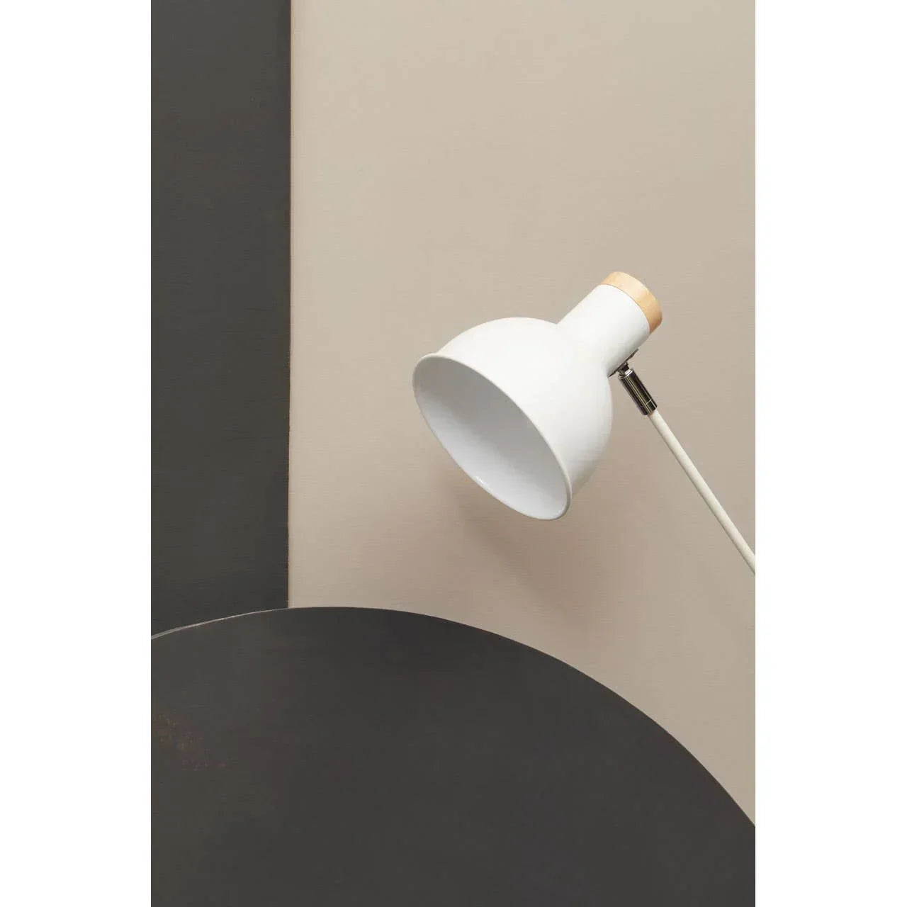 White metal desk lamp with wood detail against a beige and black geometric background