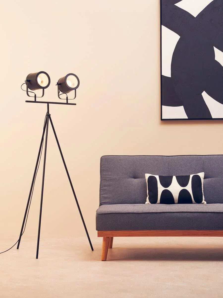 Grey fabric sofa with wooden legs, tripod floor lamp, abstract cushion and wall art