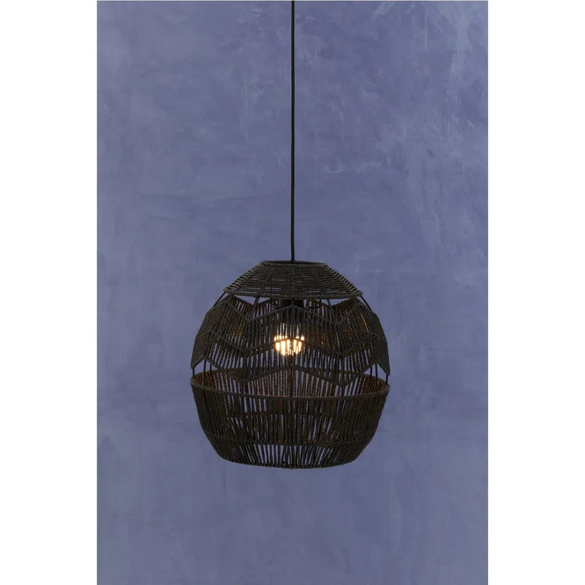 Black woven rattan pendant light with exposed bulb against blue textured wall