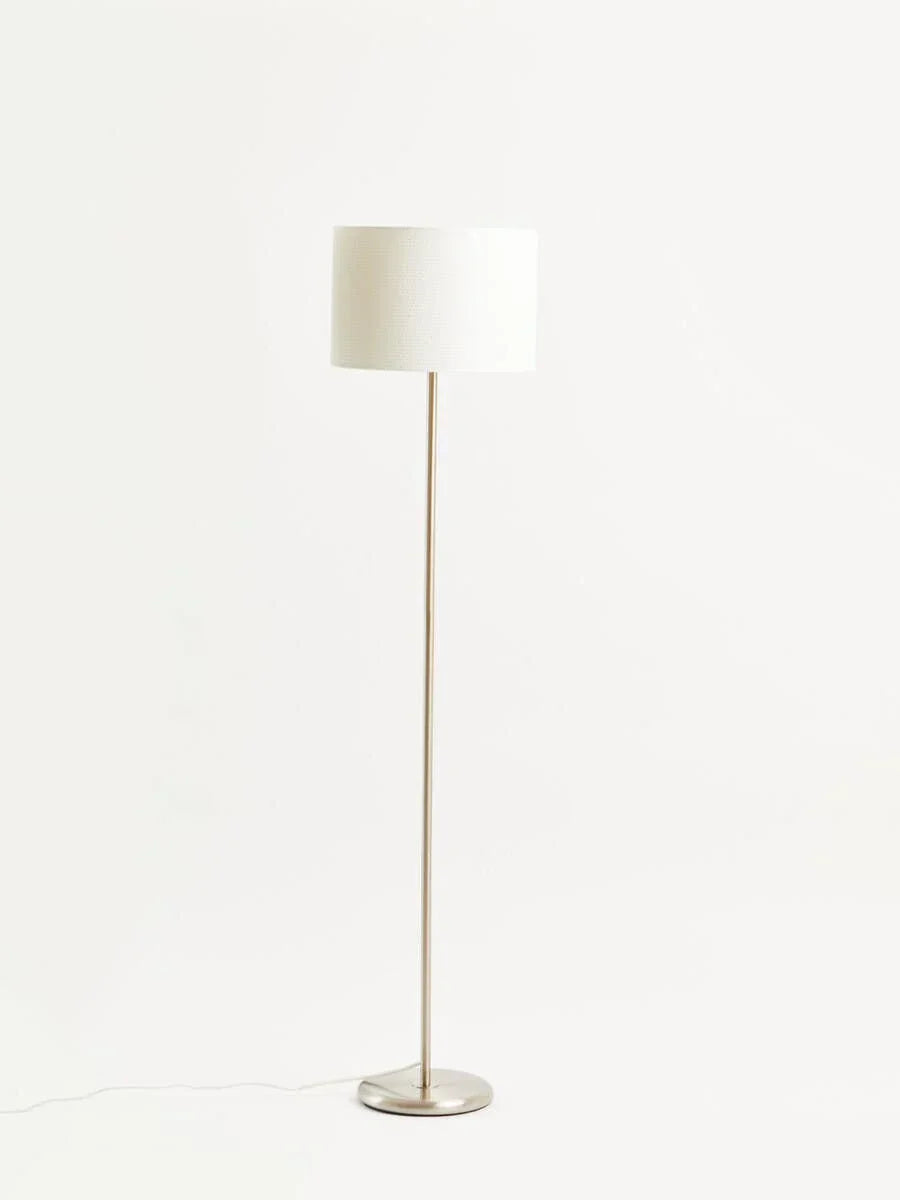 Modern floor lamp with white fabric shade and brushed metal base on white background
