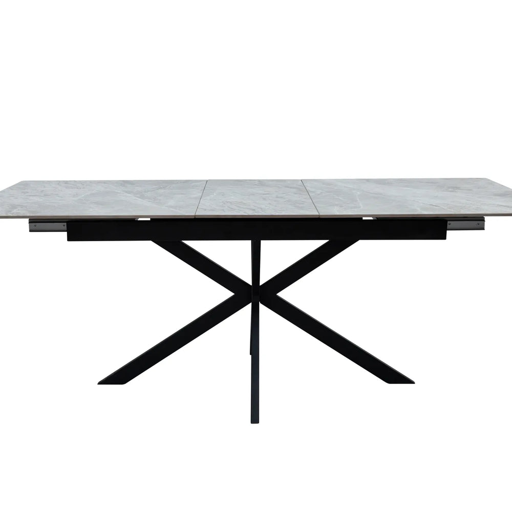A modern rectangular dining table with a gray stone-look top and a black metal X-frame base, shown against a plain white background.