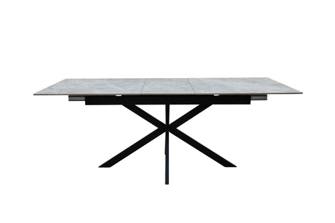 A modern rectangular dining table with a gray stone-look top and a black metal X-frame base, shown against a plain white background.