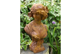 rust effect garden statue bust of woman on stone with leafy plants in background