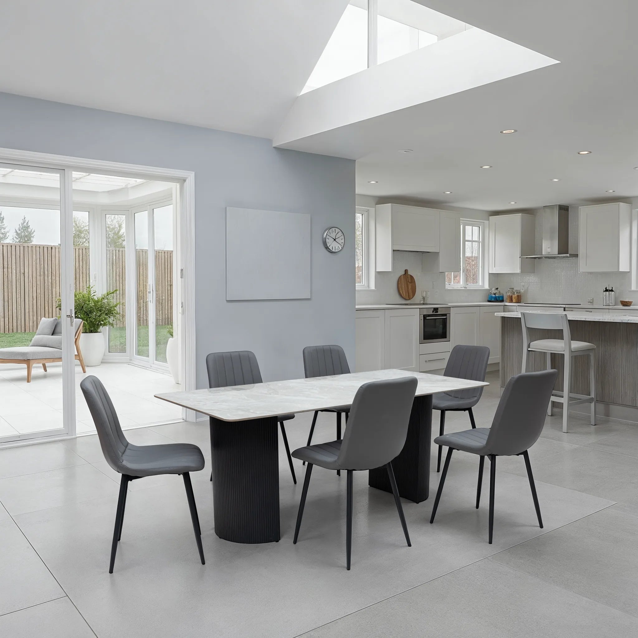 Modern kitchen with dining area featuring a white table and gray chairs.