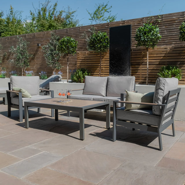 Grey outdoor garden sofa set with armchairs and rectangular coffee table on stone patio
