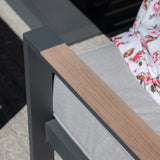 Close-up of grey garden sofa armrest with wood detail and light cushion