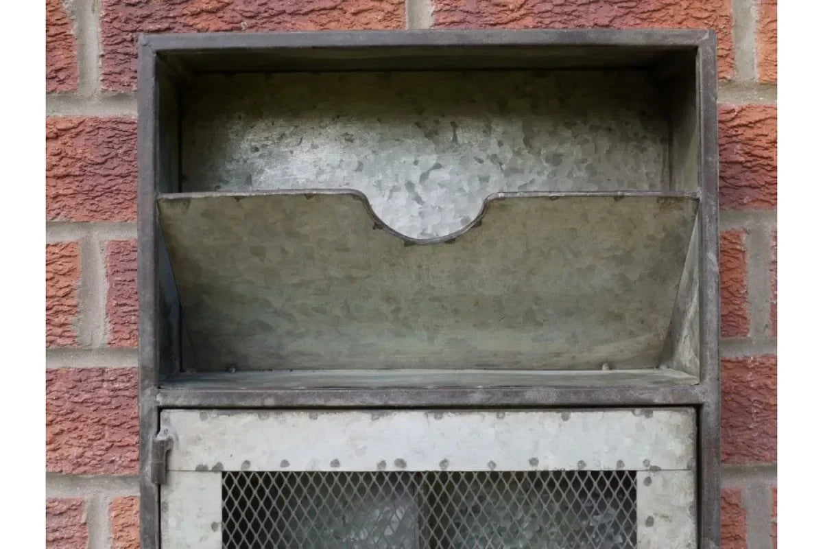 Galvanised metal post box mounted on red brick wall with open letter slot