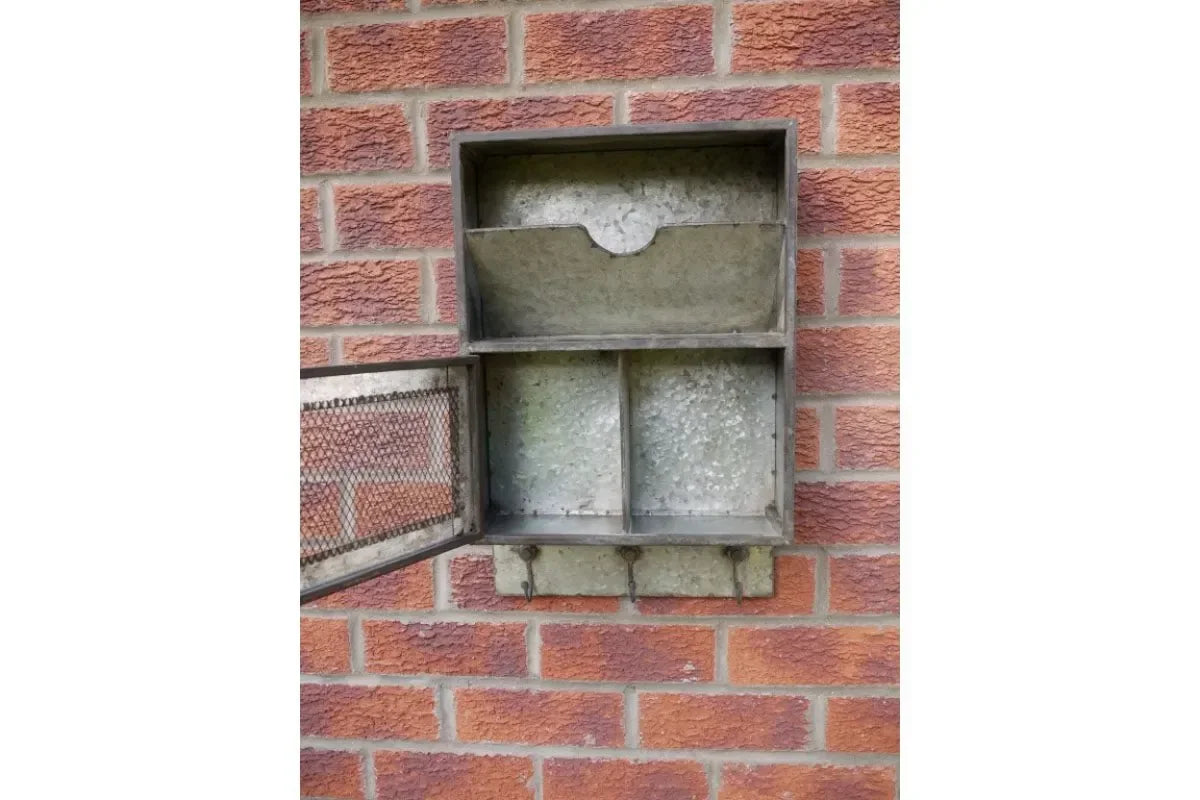 Vintage metal wall-mounted letter box with compartments and hooks on red brick wall