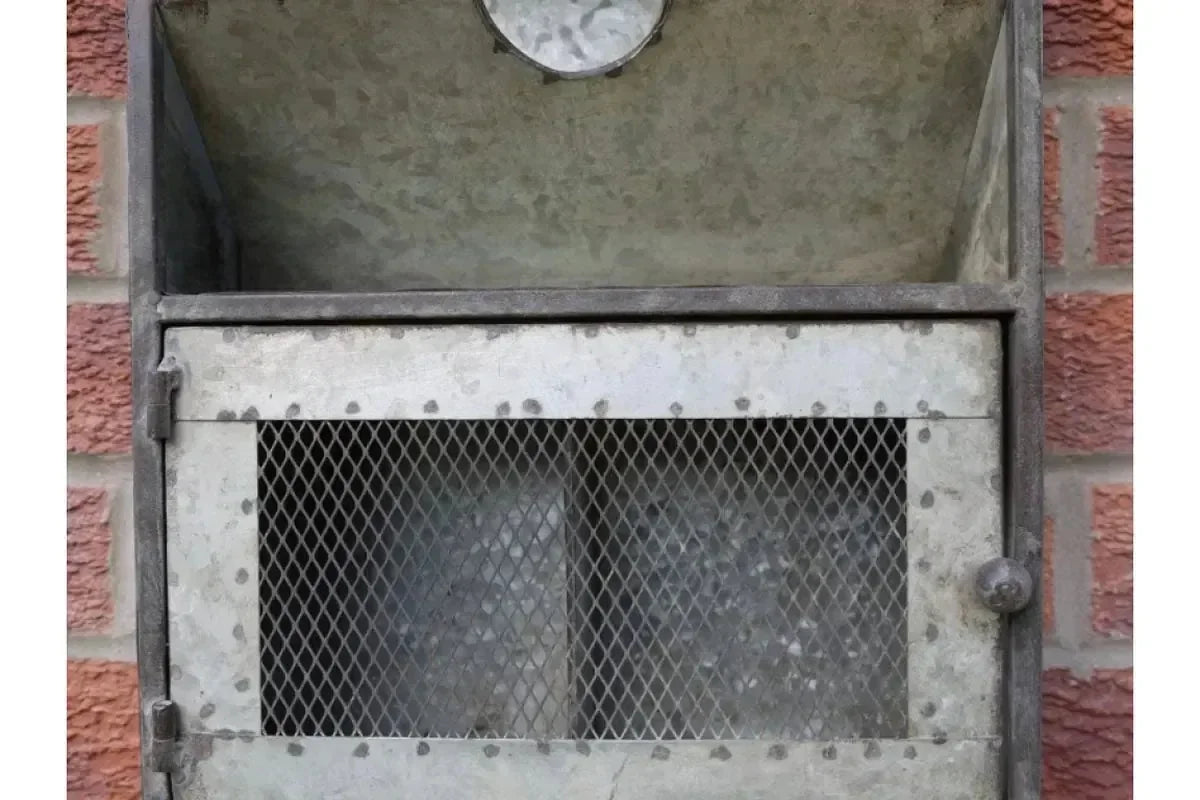 Galvanized steel outdoor parcel box with mesh door against brick wall