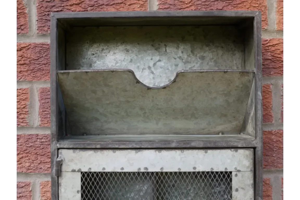 Galvanised steel outdoor letterbox with open mail slot against brick wall