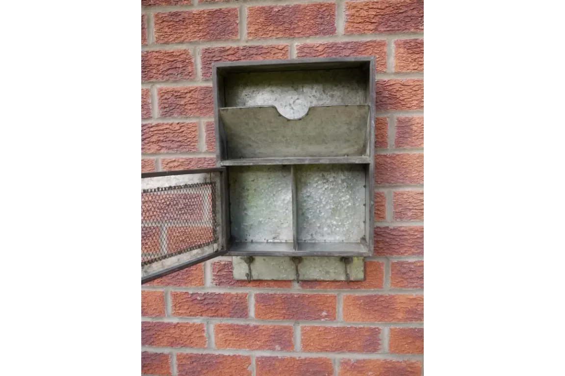 Wall mounted metal key box with open mesh door and hooks on brick exterior