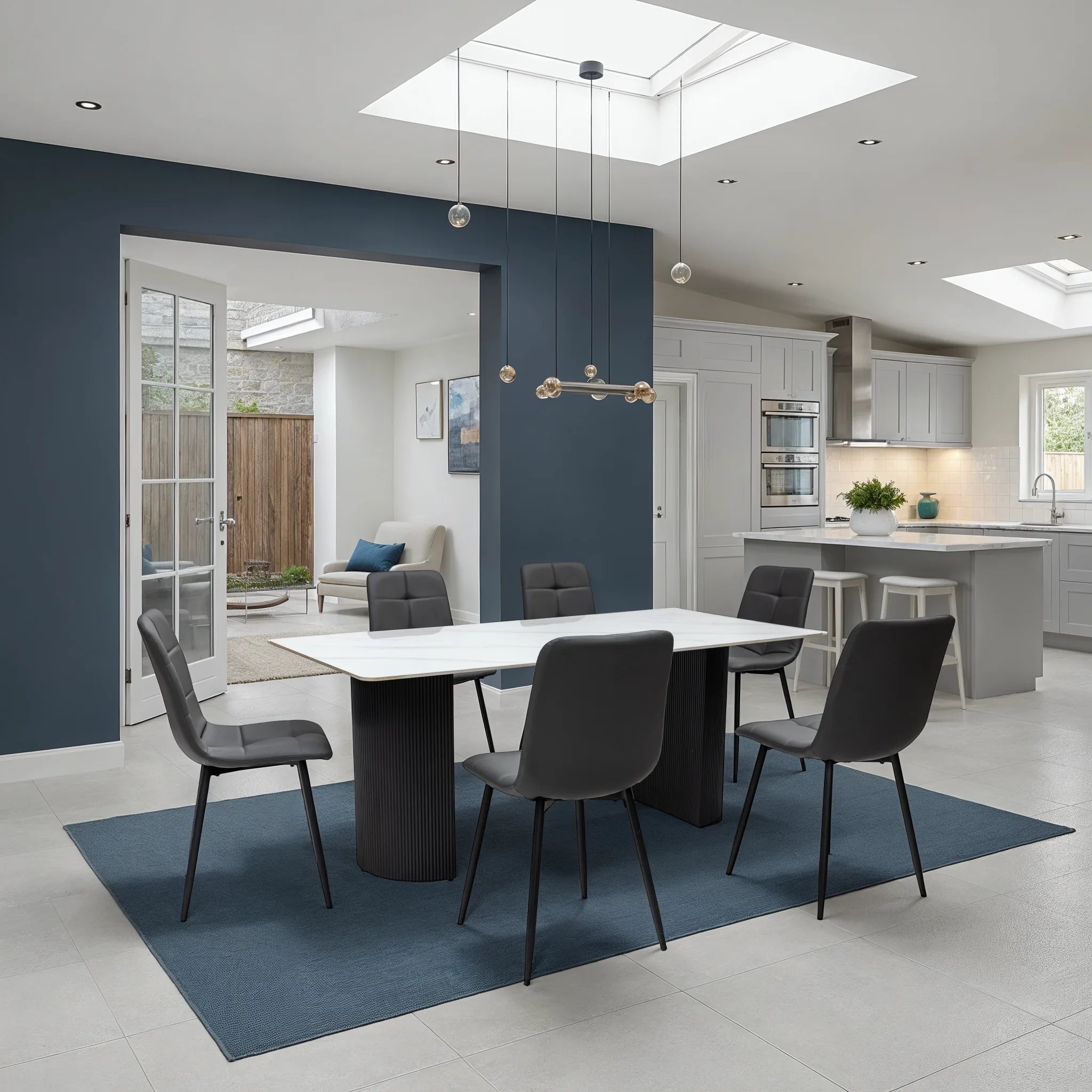Modern kitchen and dining area with a white table and gray chairs on a blue rug.