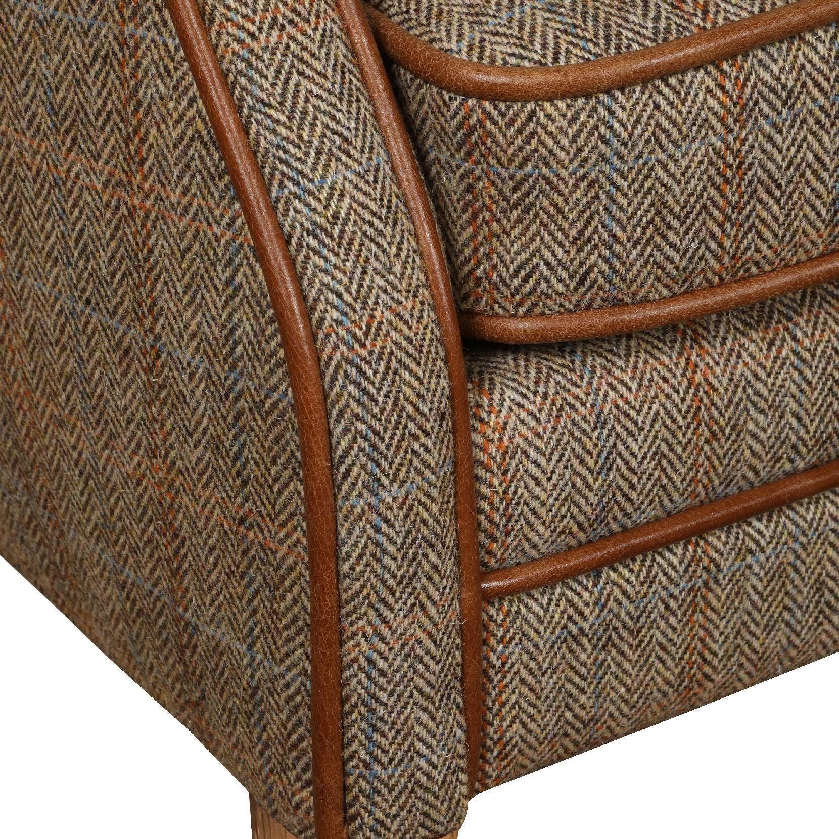 Herringbone fabric armchair with brown leather trim and light wooden leg closeup