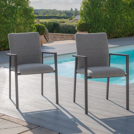 Pair of grey outdoor dining chairs with metal frames on decking by a swimming pool