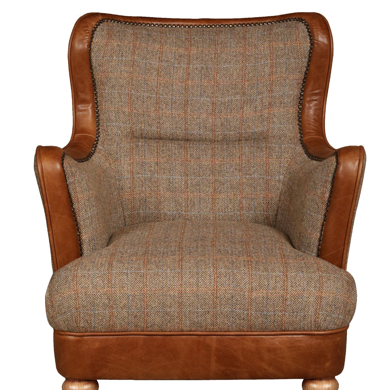 Brown leather and plaid fabric armchair with wooden legs and brass castors front view