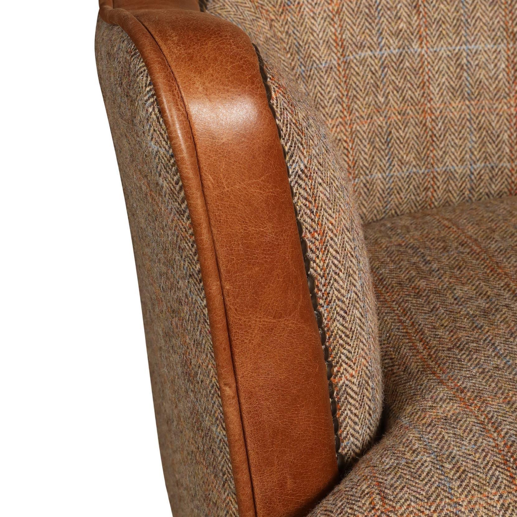 Close-up of armchair with brown leather armrest and patterned fabric upholstery