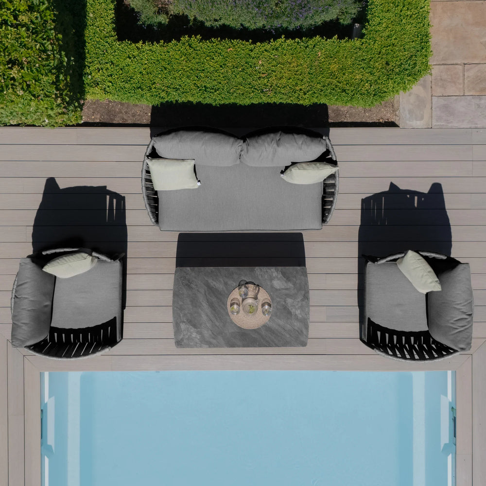 Grey outdoor sofa set with armchairs and coffee table on decking beside pool
