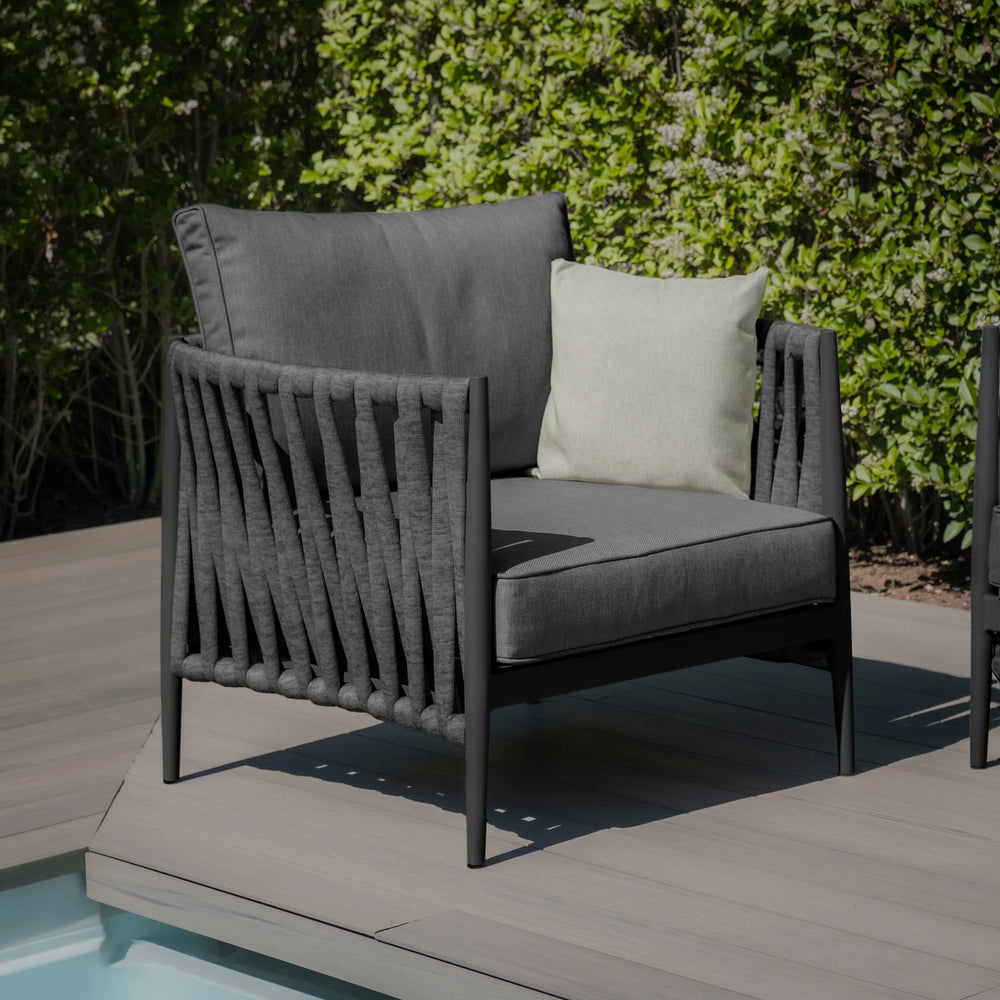 Grey outdoor lounge chair with rope detailing and cream cushion on patio by pool
