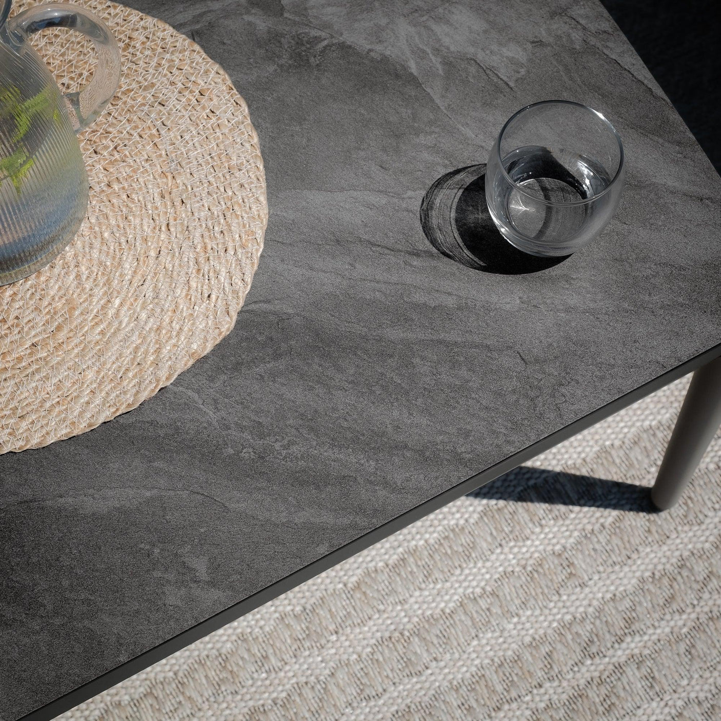 Grey stone effect coffee table with glass and jug on woven placemat