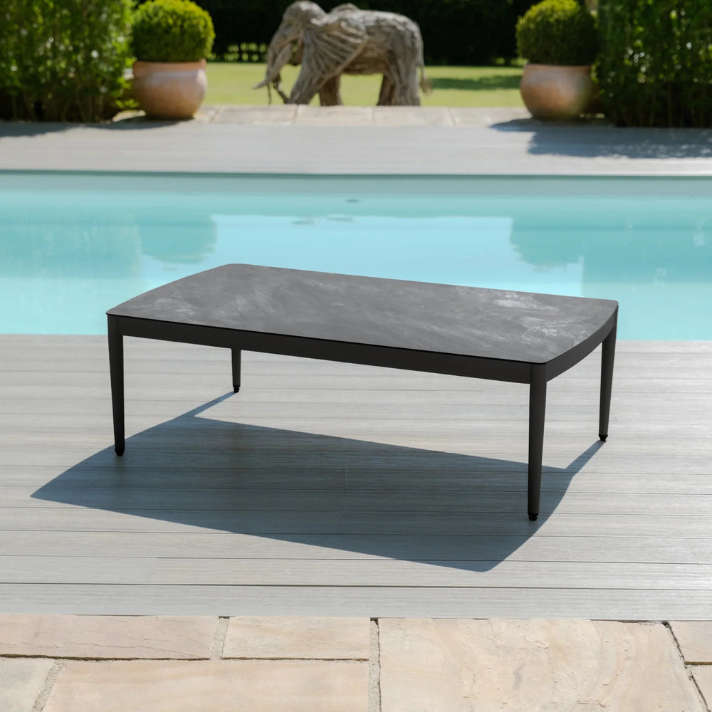 Black outdoor coffee table with metal frame on decking by a swimming pool
