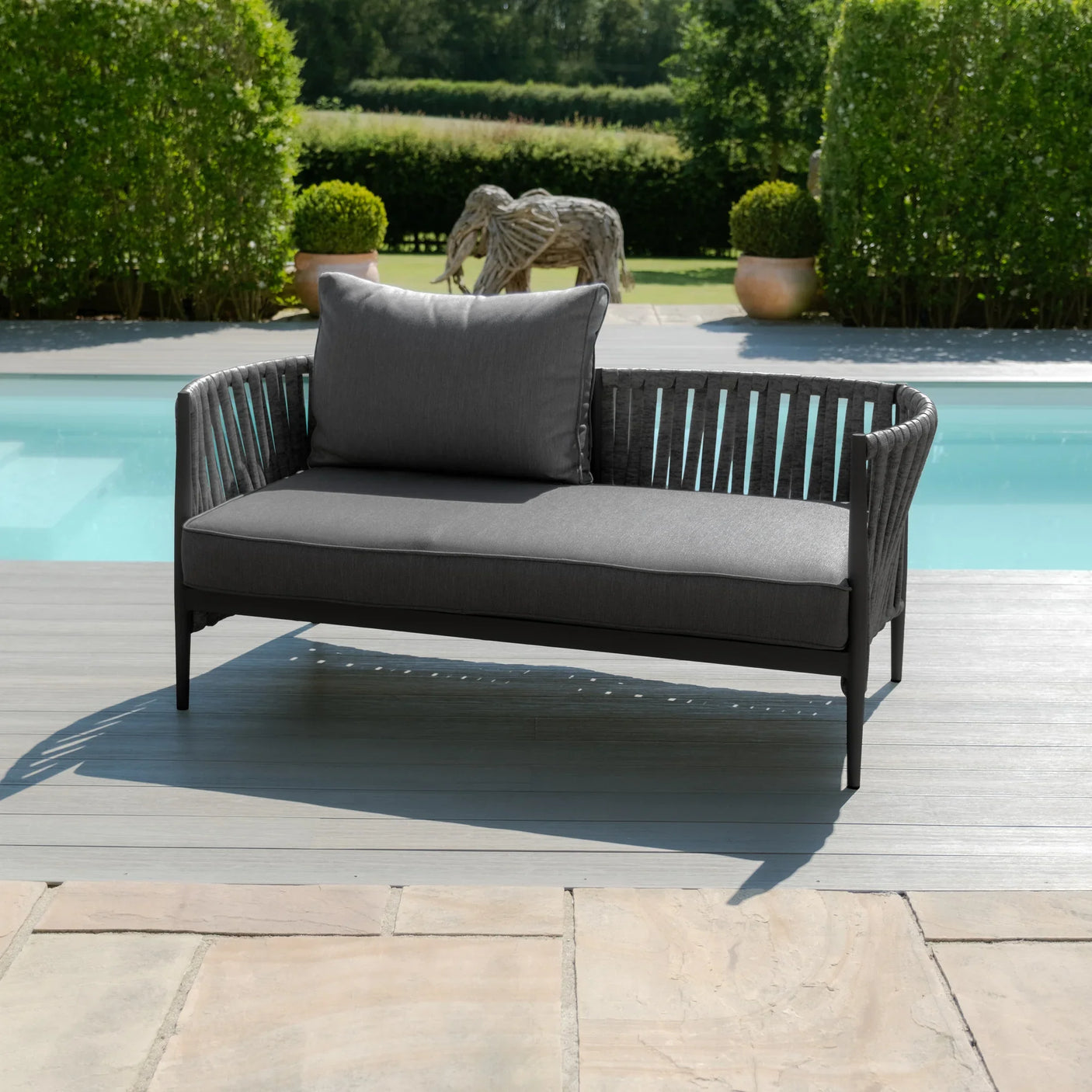 Grey outdoor sofa with rope detailing and cushion on poolside patio