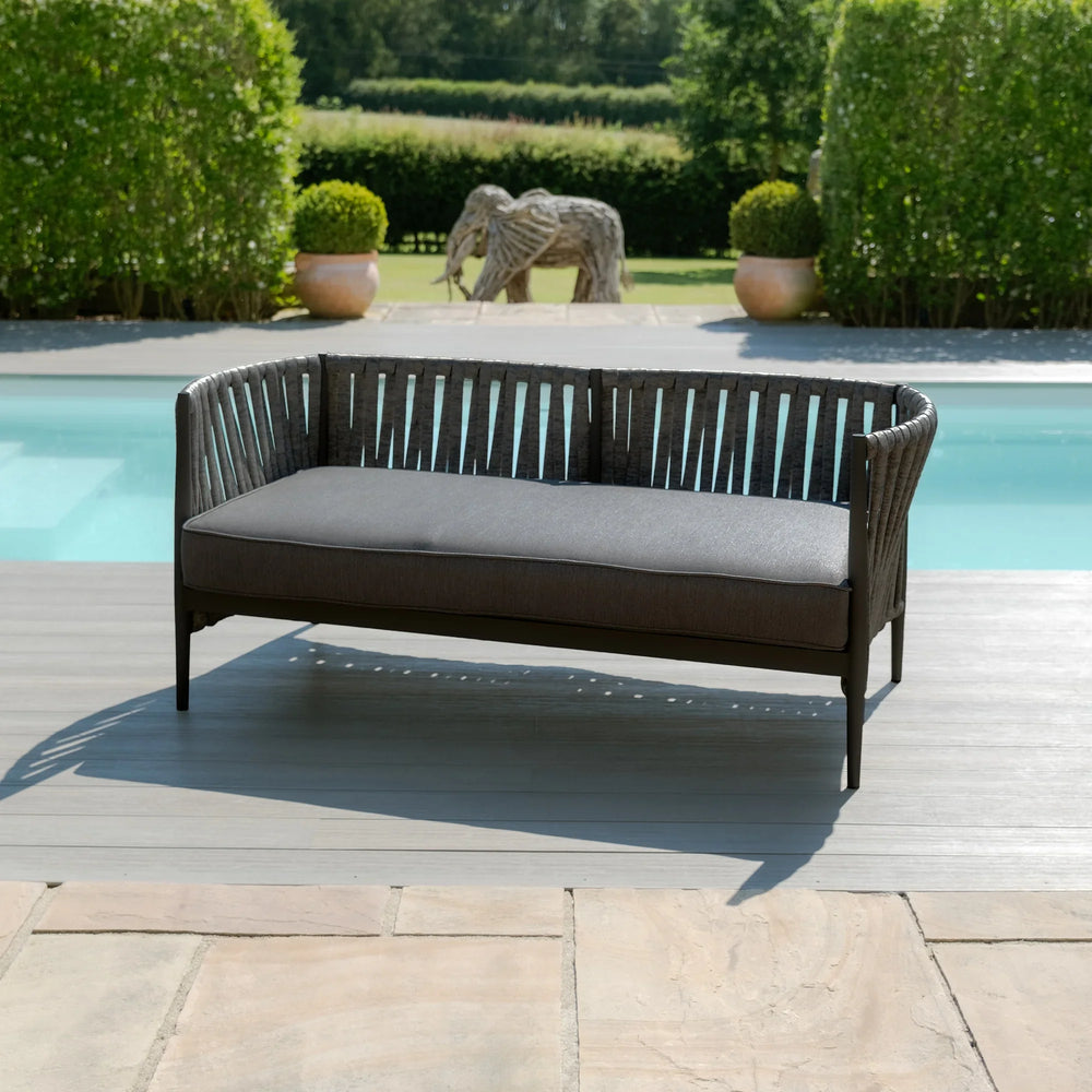 Grey outdoor sofa with woven frame and cushions by a pool on patio decking