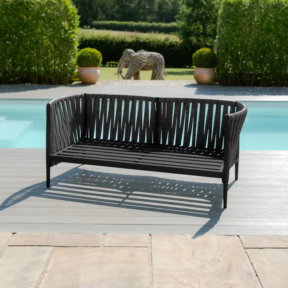 Black outdoor garden sofa with slatted design on poolside decking