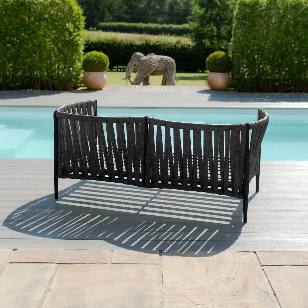 Black outdoor garden sofa with woven design placed on poolside patio