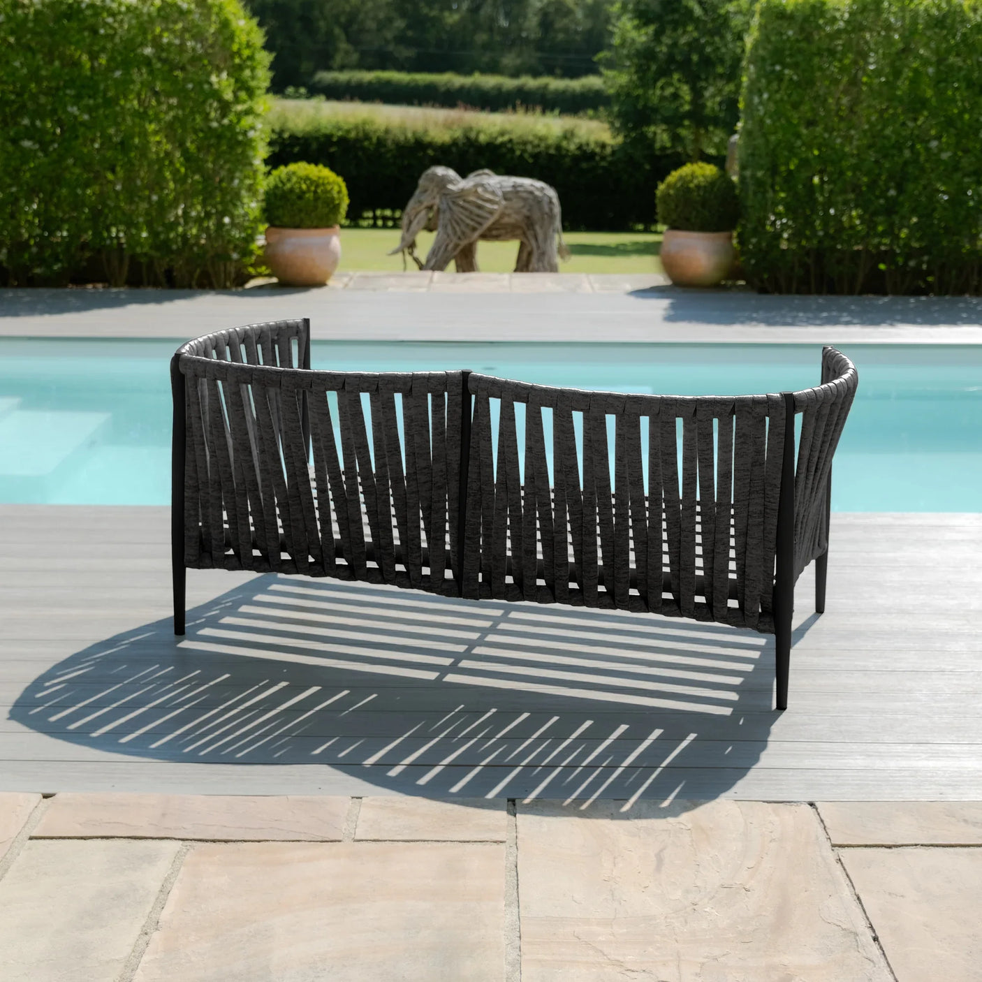 Black outdoor garden sofa with woven design placed on poolside patio