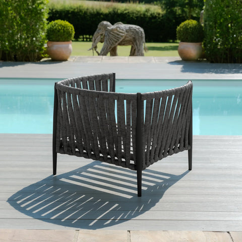 Charcoal outdoor lounge chair with woven rope design on decking beside swimming pool