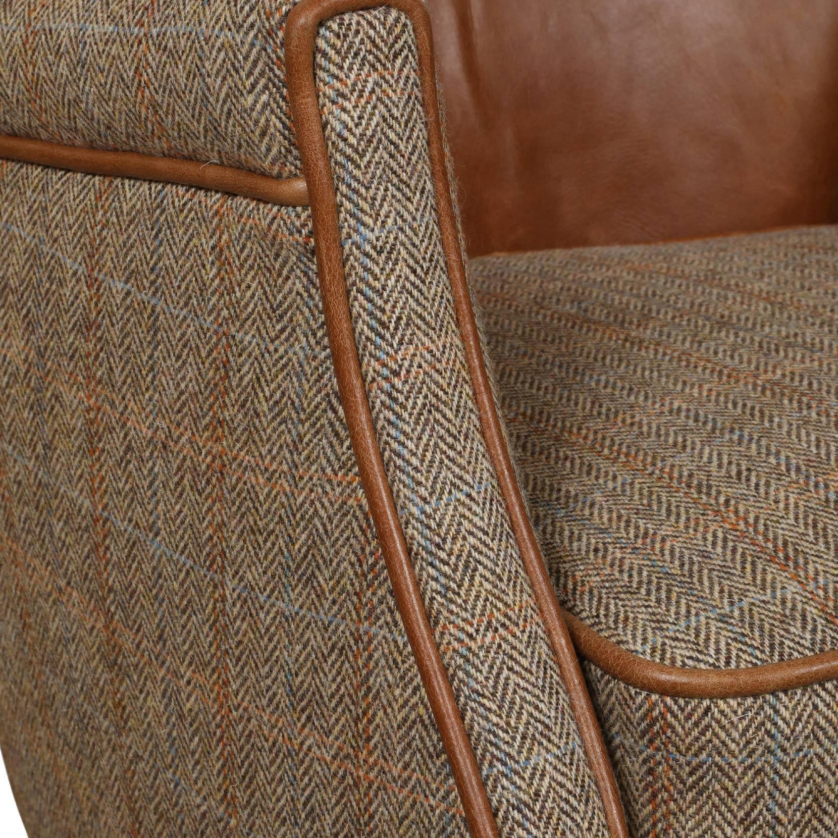 Closeup of tweed armchair with brown leather backrest and herringbone fabric upholstery