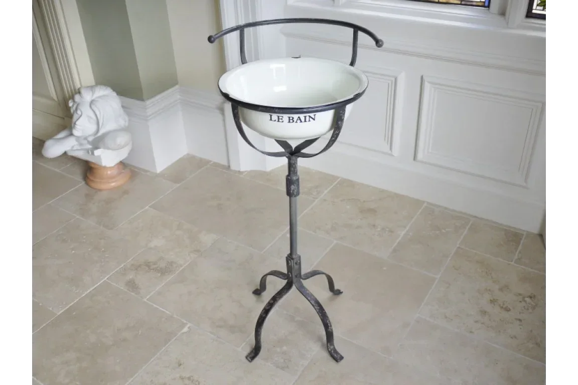 White enamel wash basin on vintage black metal stand with tripod base, Le Bain text visible