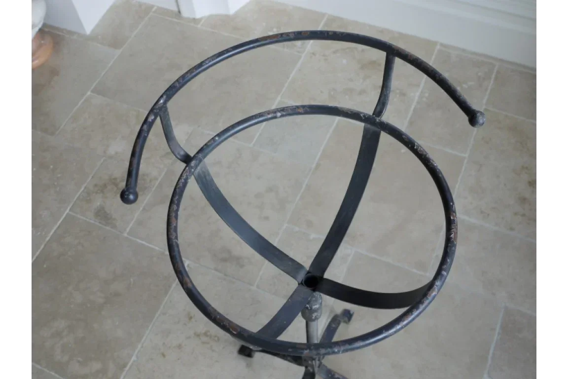 Black wrought iron plant stand with round frame on tiled floor