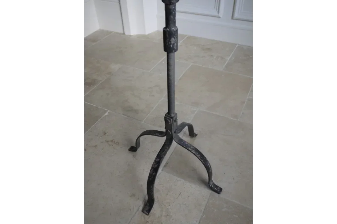 Black metal table base with three curved legs on tiled floor