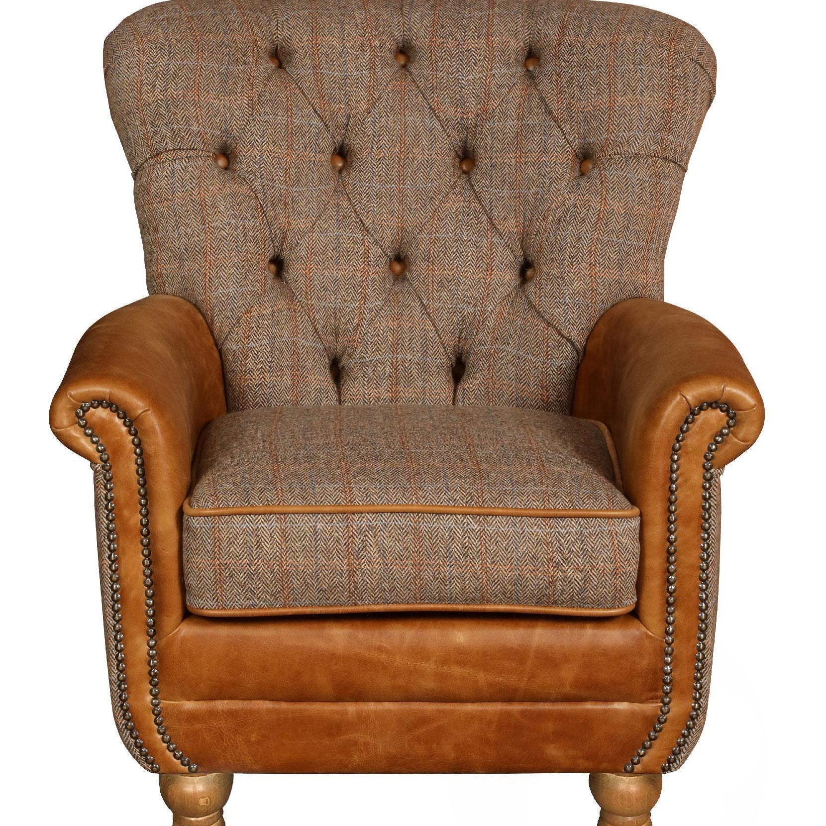 Button-tufted fabric armchair with brown leather arms and wooden legs, front view