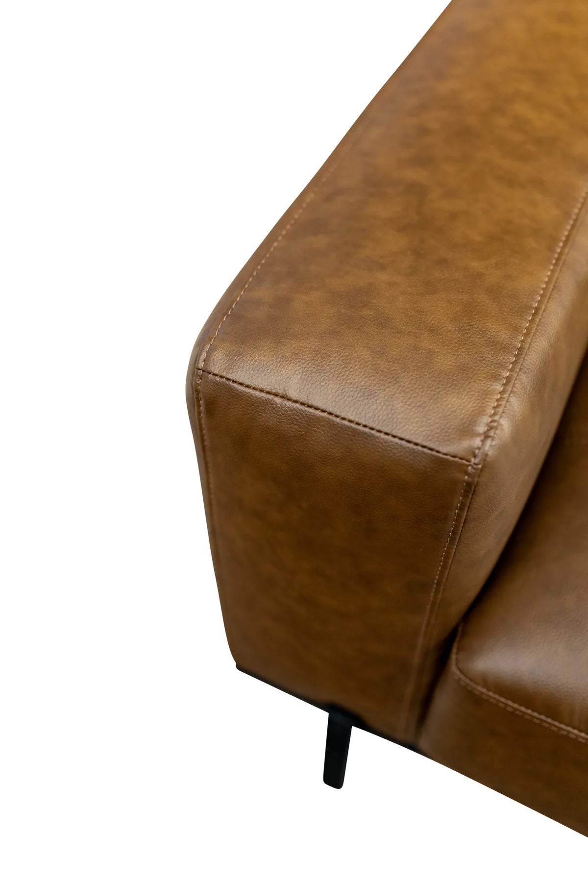 Close-up of a brown faux leather sofa armrest showing the texture and stitching, with a small black metal leg visible against a white background.