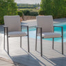 Pair of outdoor dining chairs with grey cushions beside a swimming pool on decking