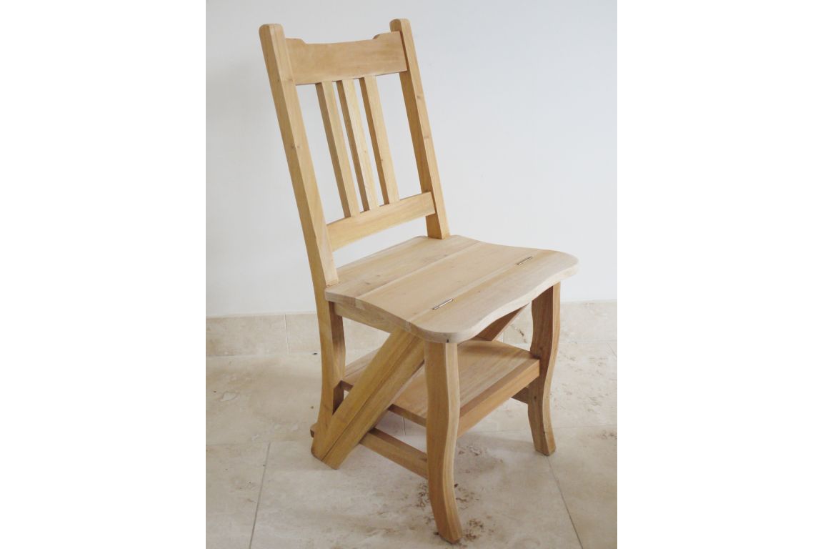 Unfinished light wood chair with vertical slat back, curved seat, and lower step shelf, shown from a side angle.