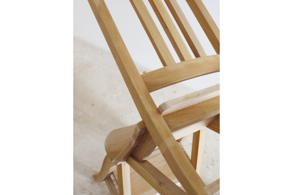 Unfinished wooden chair with slatted back and step stool feature, angled view on light stone floor.