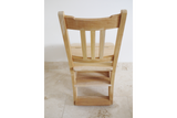 Unfinished wooden step chair with vertical slats, viewed from the back on a tiled floor against a white wall.