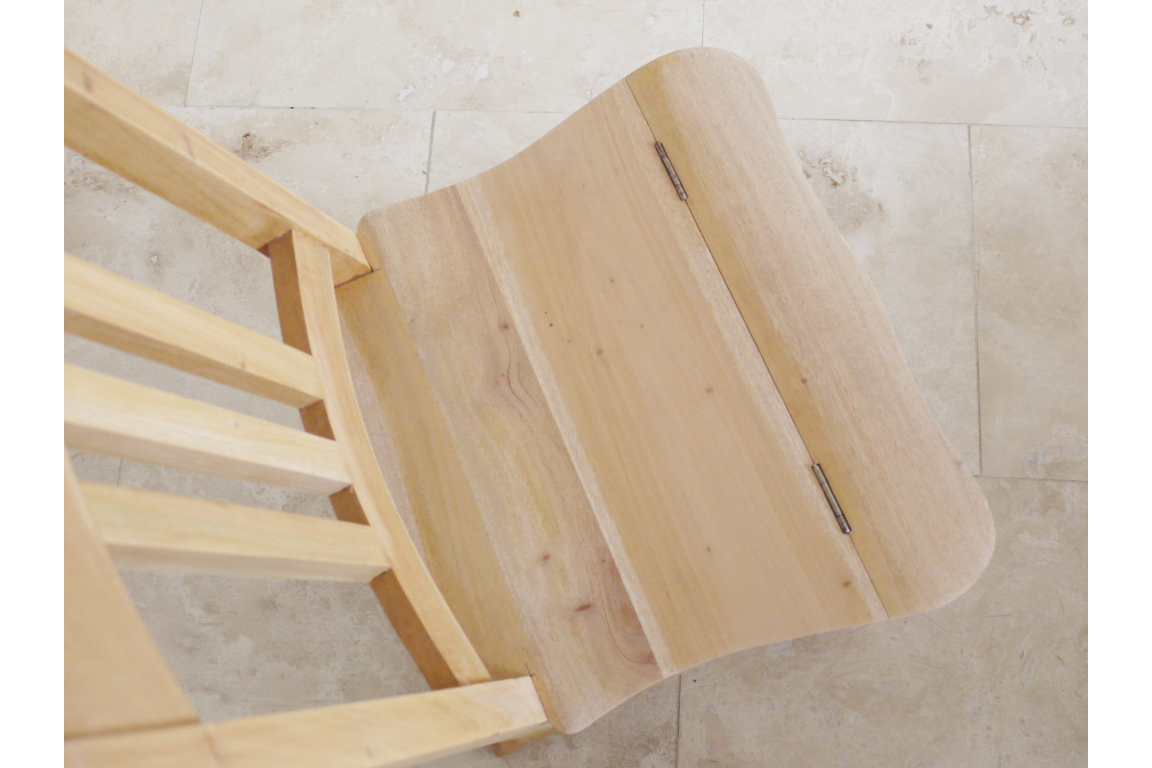 Unfinished light wood chair with a hinged seat viewed from above on a tiled floor.
