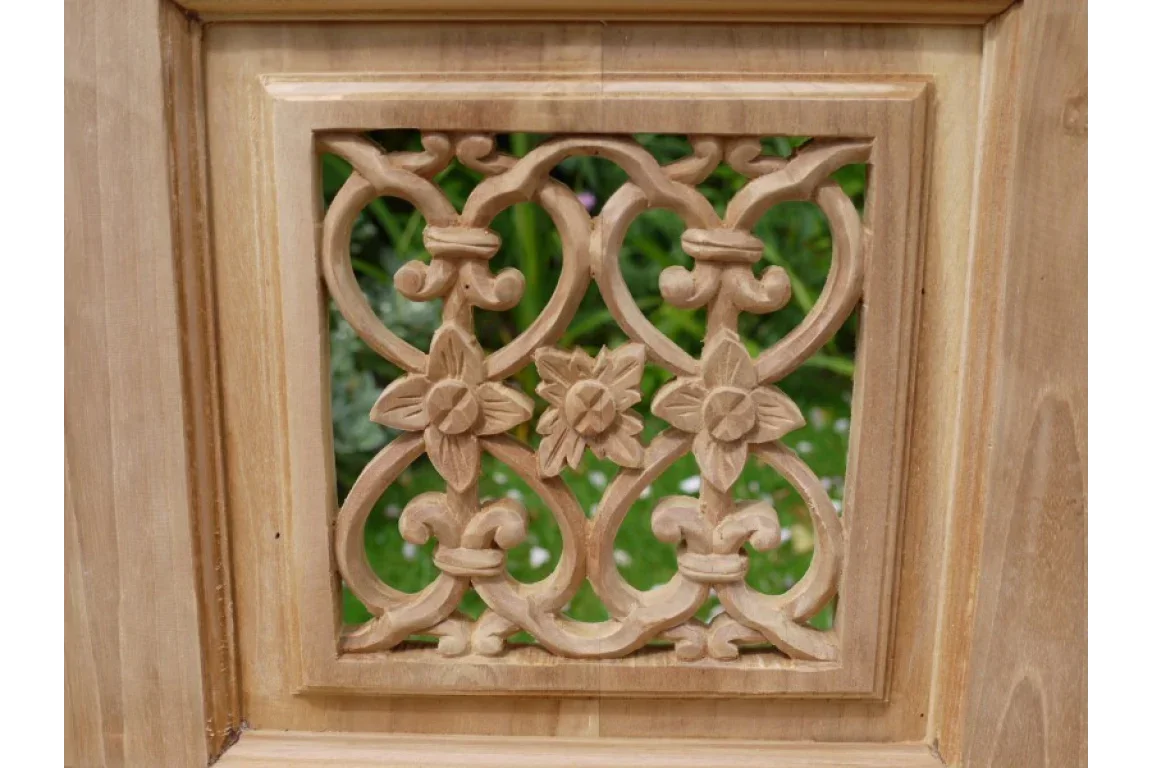 Close view of carved wood panel with floral motifs and natural finish