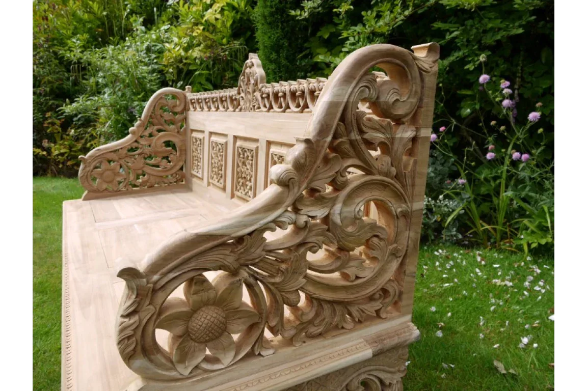 Hand-carved wooden garden bench with ornate floral and scroll detail on armrest