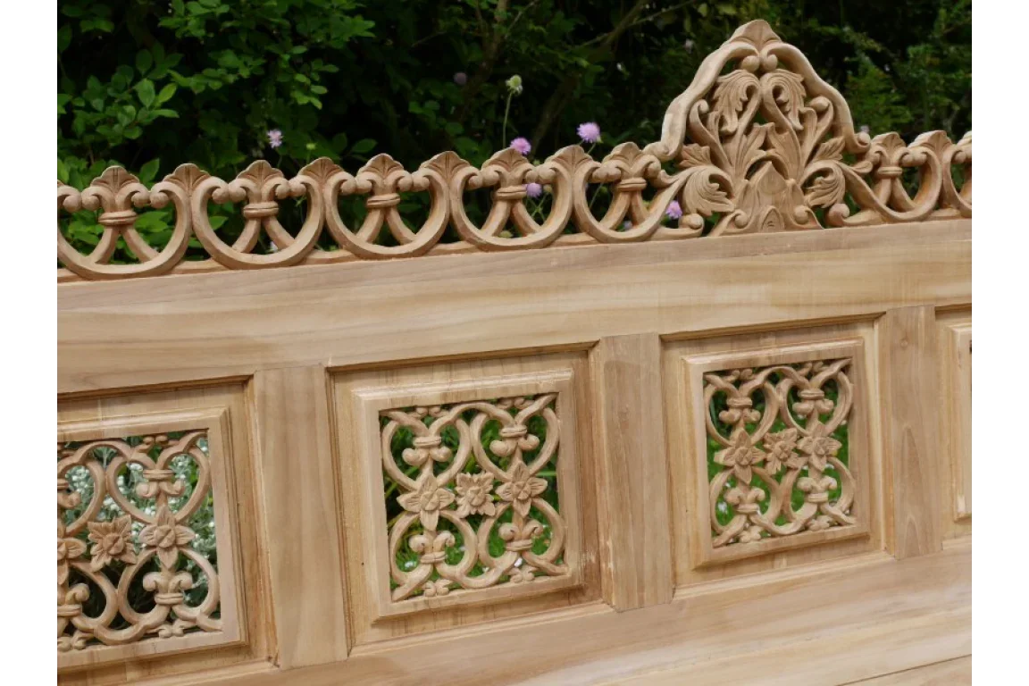 Teak garden bench backrest with detailed floral and scroll wood carving outdoors