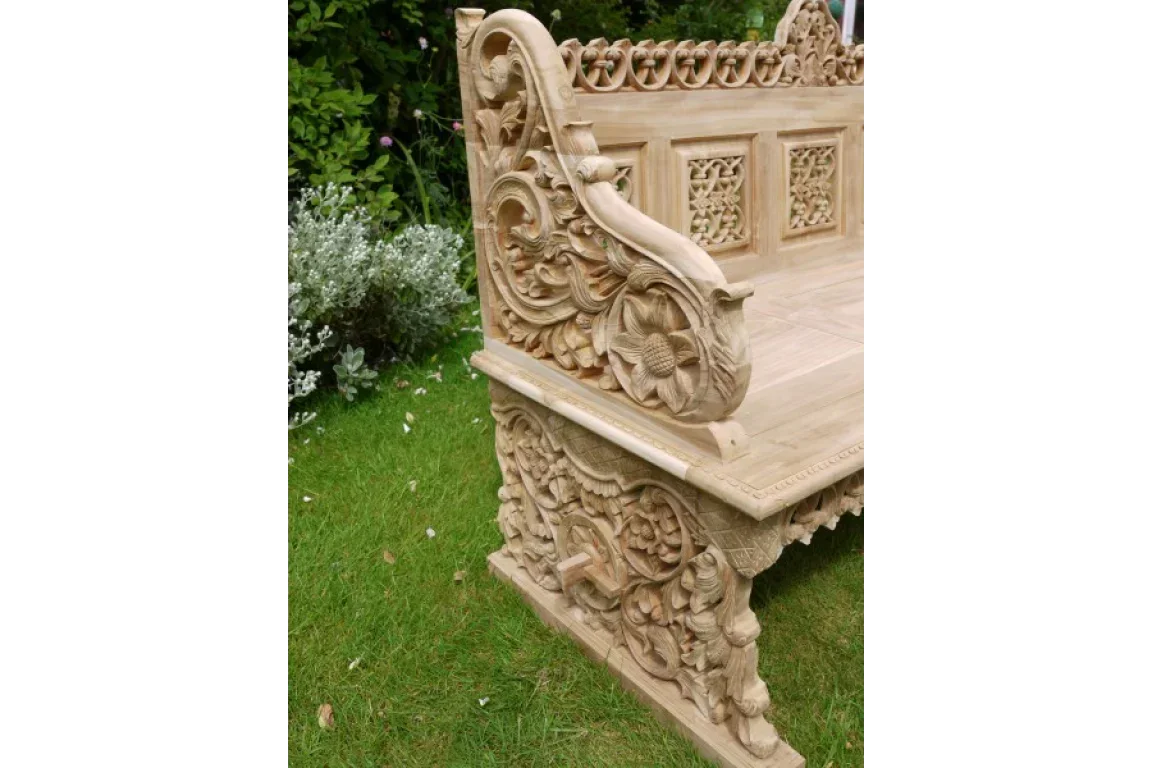 Hand-carved wooden garden bench with detailed floral and scrollwork designs on lawn