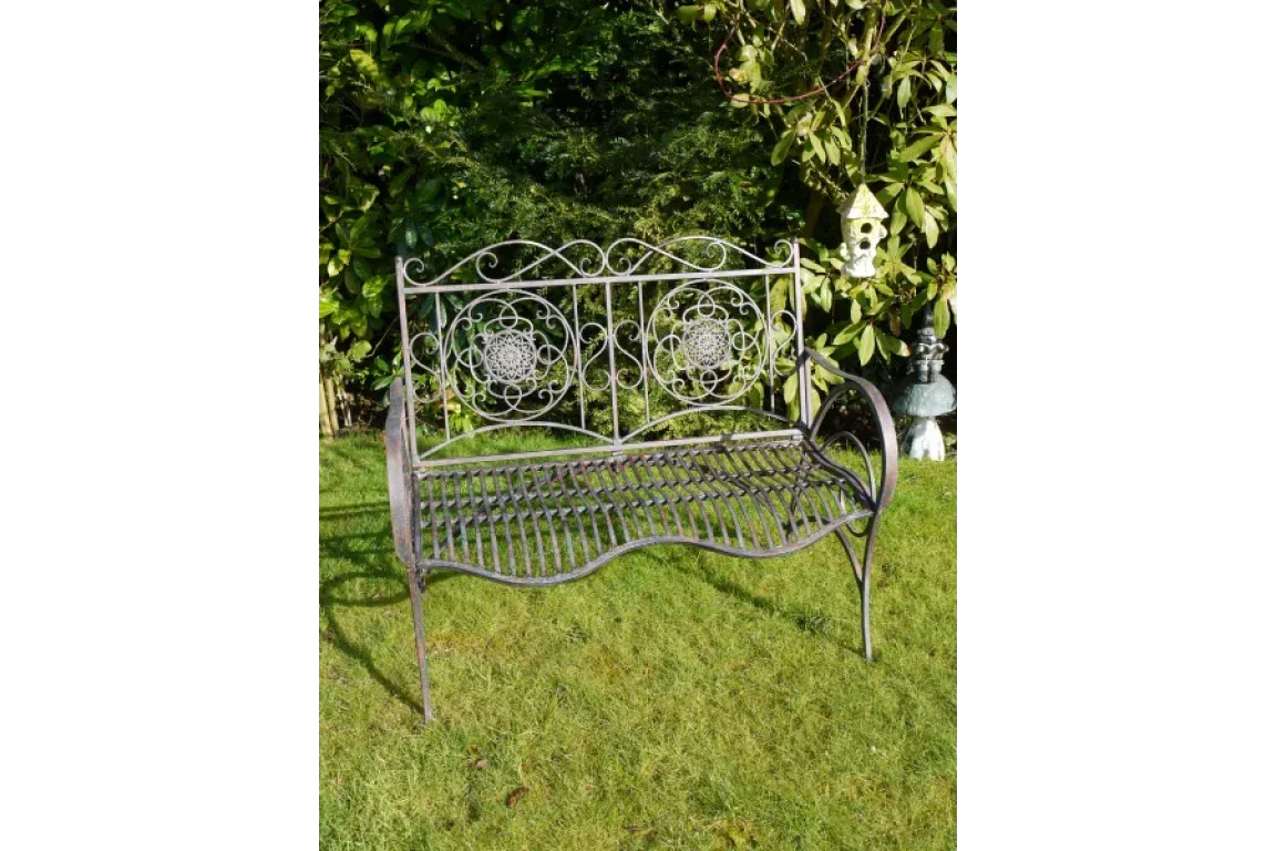 Black wrought iron garden bench with decorative backrest on lawn